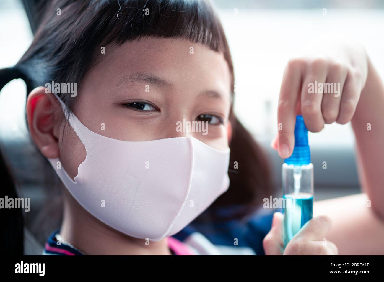 Little child girl wear face mask and holding sanitizer prevent virus and plague infection, prevent covid-19 virus Stock Photo