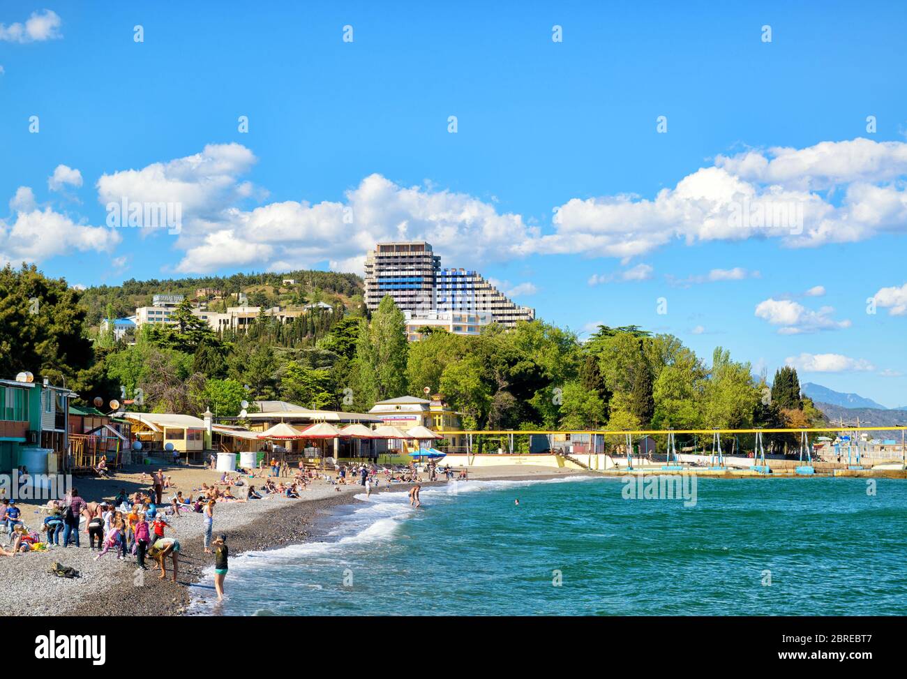 ALUSHTA, RUSSIA - MAY 15, 2016: Tourists sunbathe and swim at the beach. Alushta is a well-known resort in the Crimea. Stock Photo