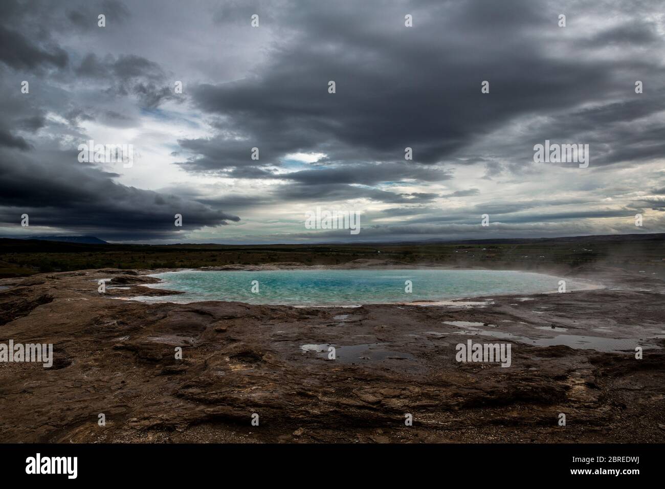 hot spring at the Geysir site in central Iceland. The water is heated by geothermal energy smells like egg from the sulfur rising from the earth Stock Photo