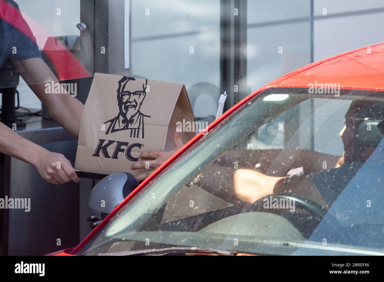A member of staff hands an order to a customer at a KFC drive-thru in Leicester as the fast food chain reopened hundreds of its restaurants as drive-thru and pick-up locations after the introduction of measures to bring the country out of lockdown. More than 500 locations will be reopened with a limited menu by the end of the week. Stock Photo