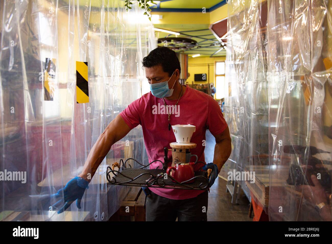 Cafe owner Francini Osorio serves customers in a trial phase during the coronavirus lockdown. Osorio has installed an air purifier and 35 clear shower curtains, which will divide customers and tables, in the Francini Cafe De Colombia, Worcester, ready for the re-opening of his business as lockdown restrictions are eased. Stock Photo
