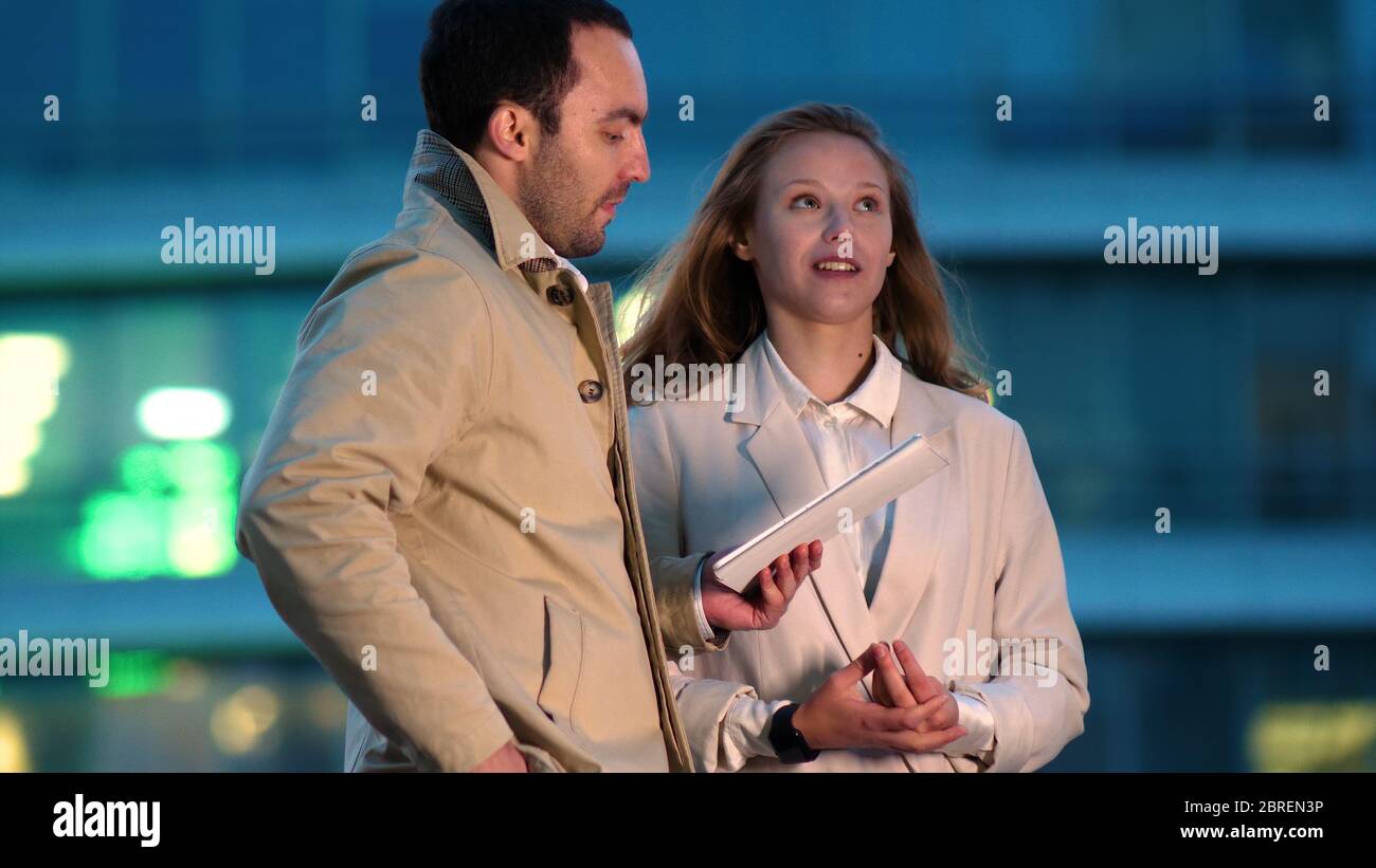 Two young work colleagues using a digital tablet while standing Stock Photo