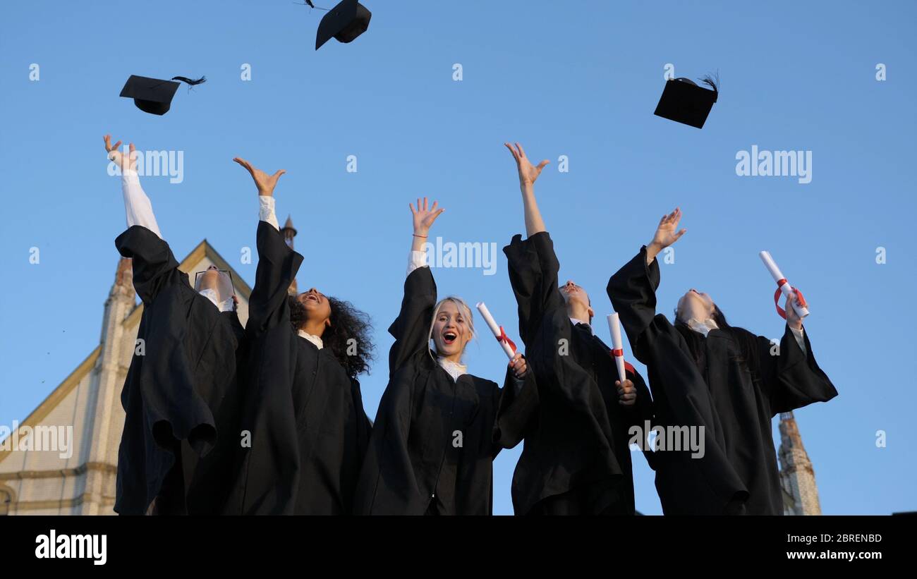 Group of graduates throwing their caps up in the air happily Stock