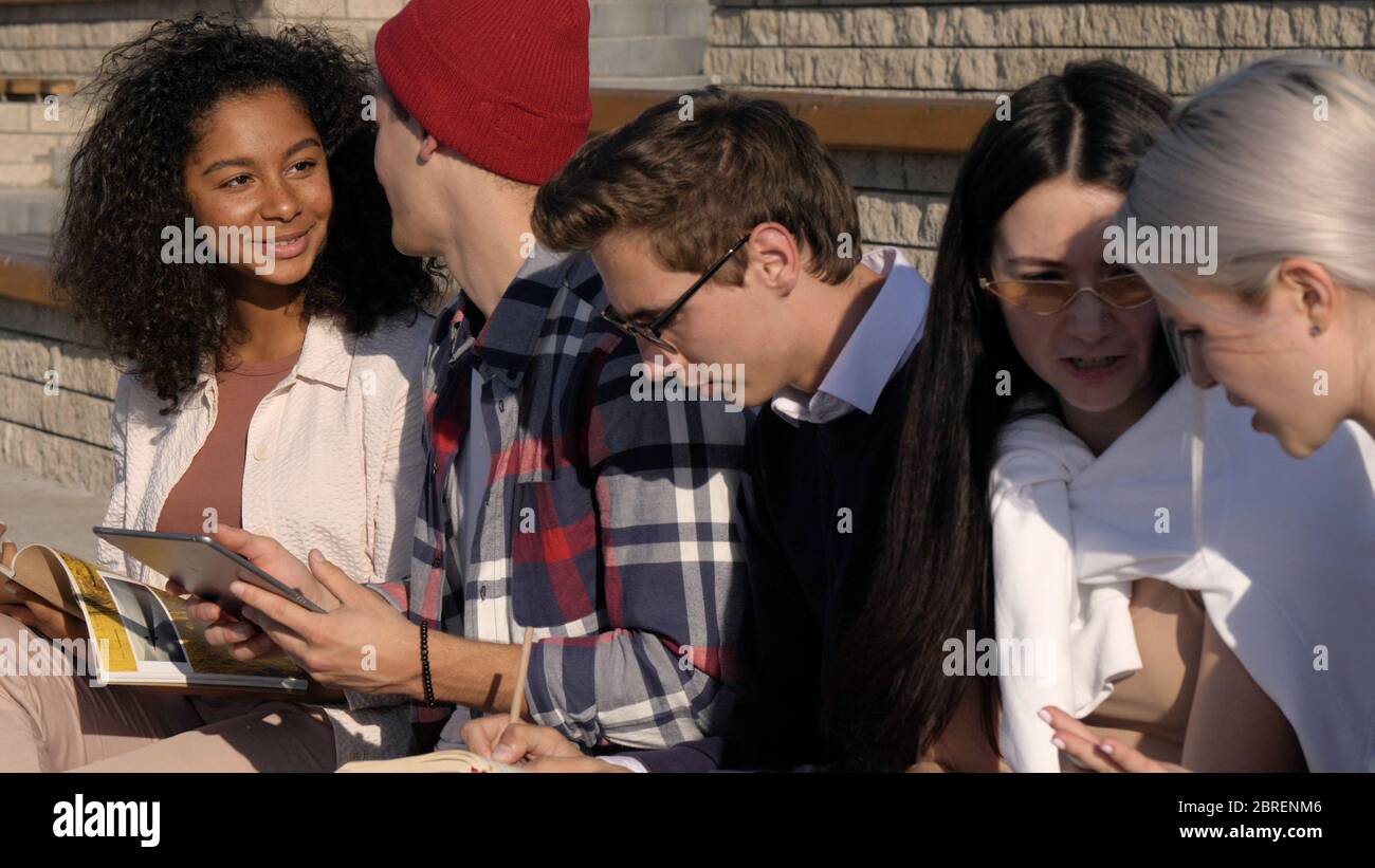 Multi-ethnic students hanging out outdoors doing some homework. Stock Photo