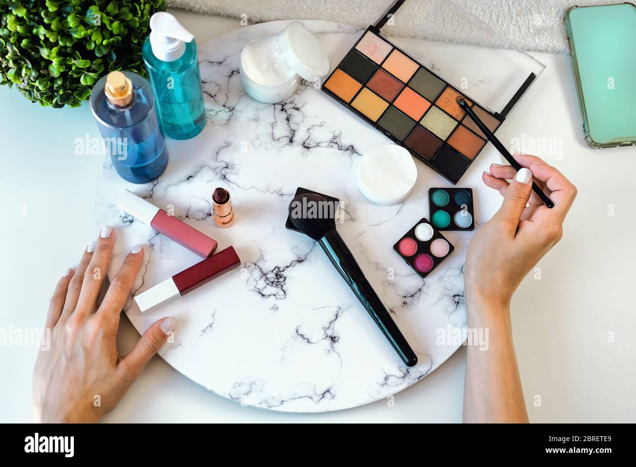 Top view young woman doing makeup at home - Closeup female hands applying make up - Cosmetic and skincare advertising concept Stock Photo