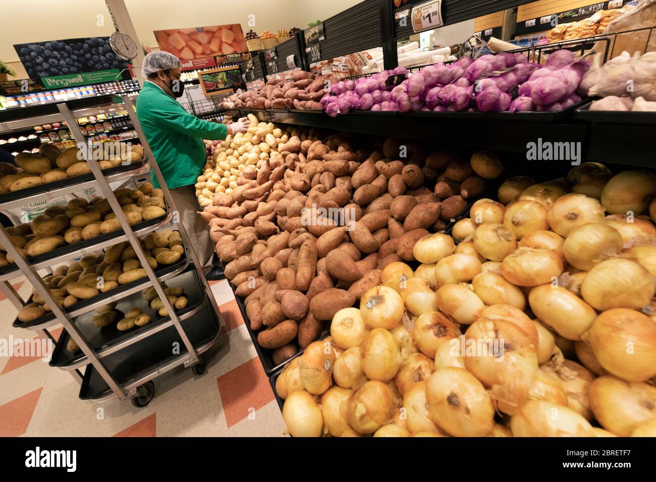 Man wearing protective mask restocking supermarket vegetable section Stock Photo