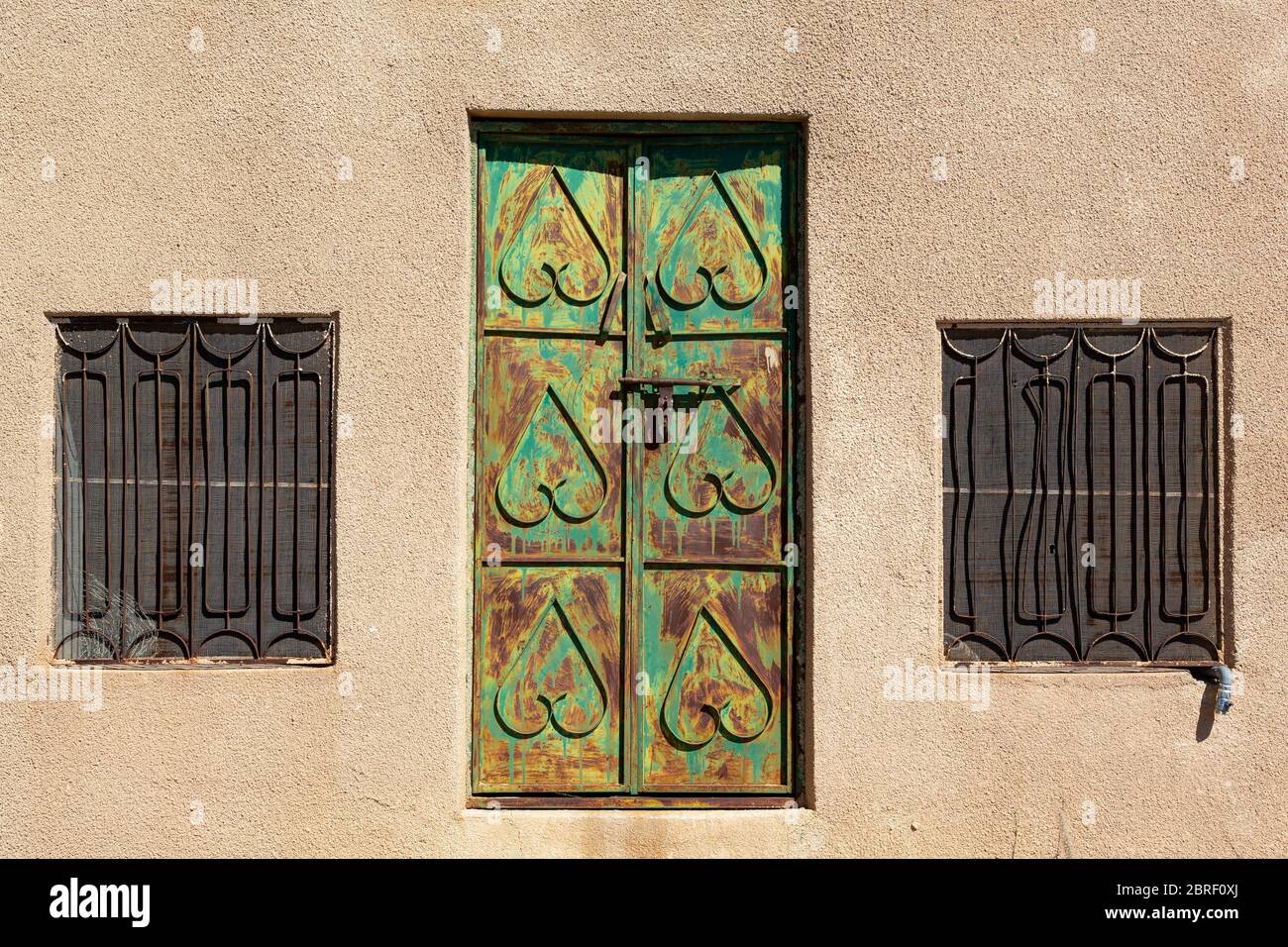 Rusty traditional Oman door on Jabal Shams that was formerly green, along with two windows Stock Photo