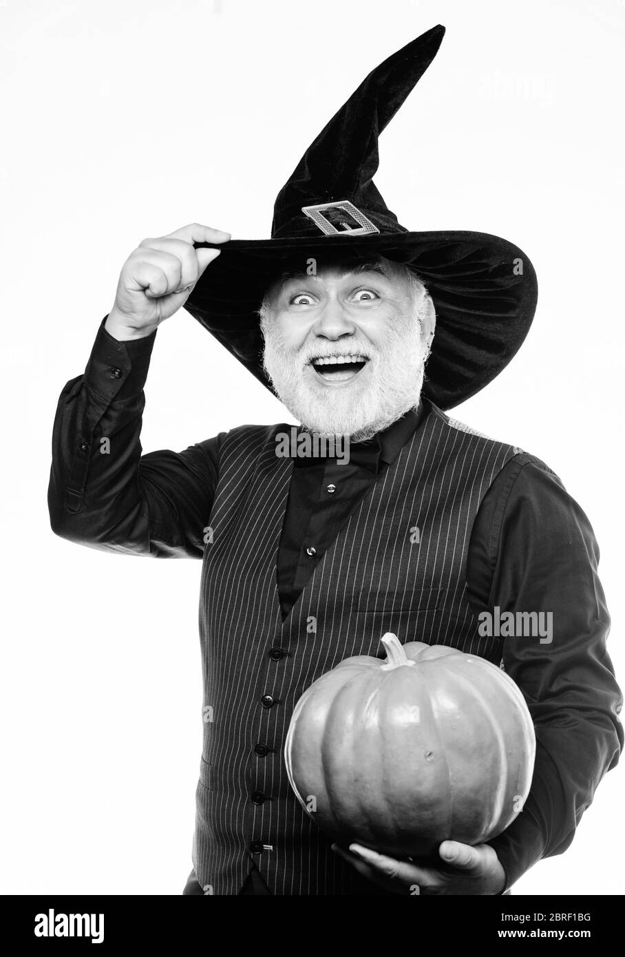 halloween traditions. evil wizard hold orange pumpkin. bearded man ready for halloween party. Stargazer in holiday costume. Traditional food. happy halloween. mature man magician in witch hat. Stock Photo