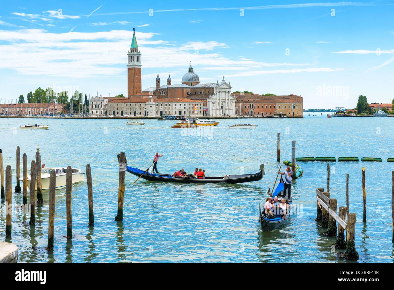 Venice, Italy - May 21, 2017: Gondolas with tourists are sailing along the Venetian lagoon. San Giorgio Maggiore in the background. The gondola is the Stock Photo