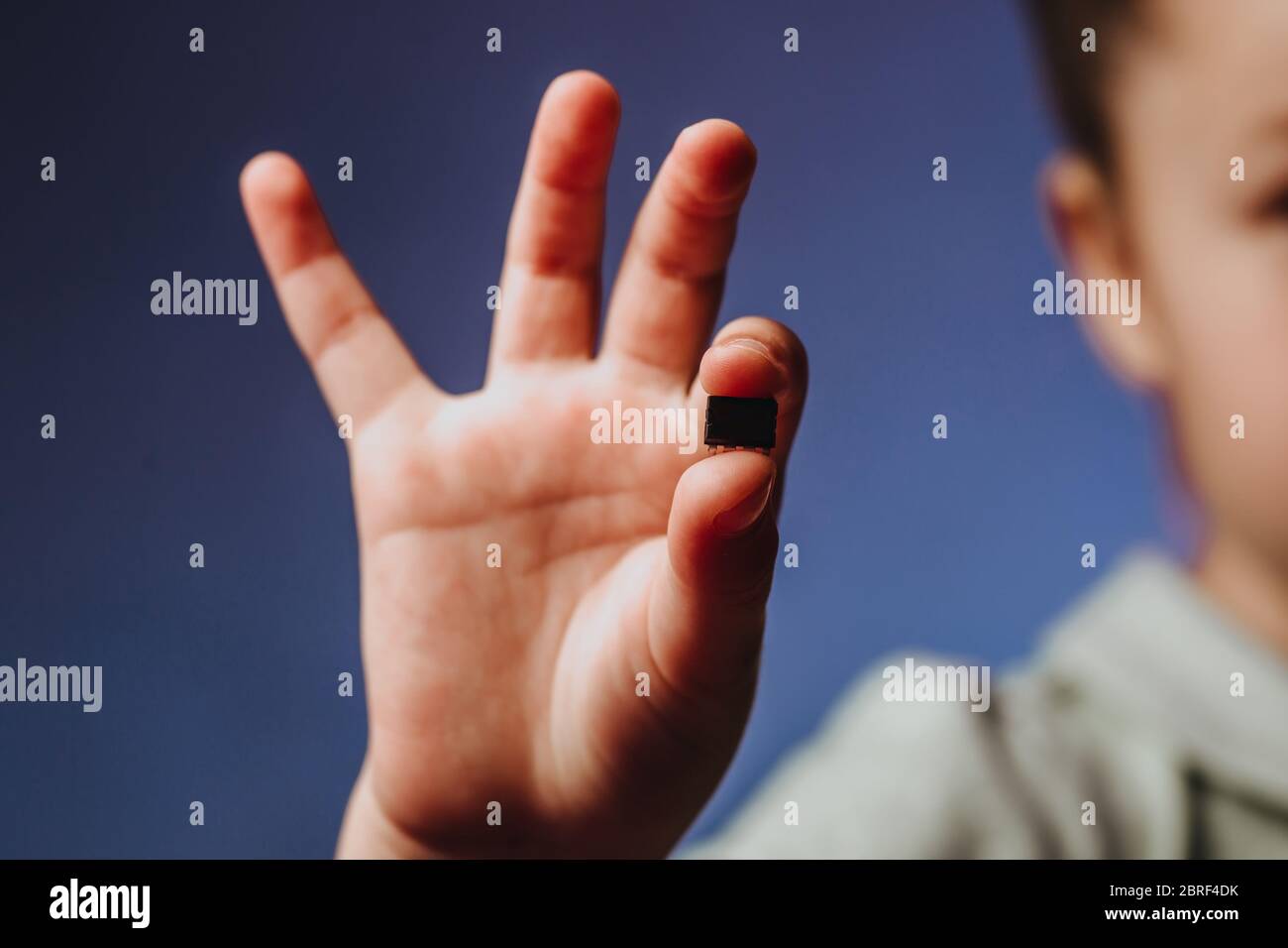 A girl holds in her hand and examines a small black chip. Chipization of people after an epidemic coronavirus. Stock Photo