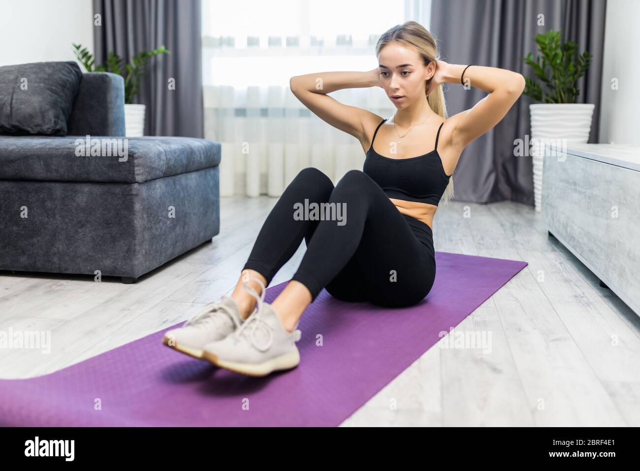 Woman doing sit-ups in home gym Stock Photo