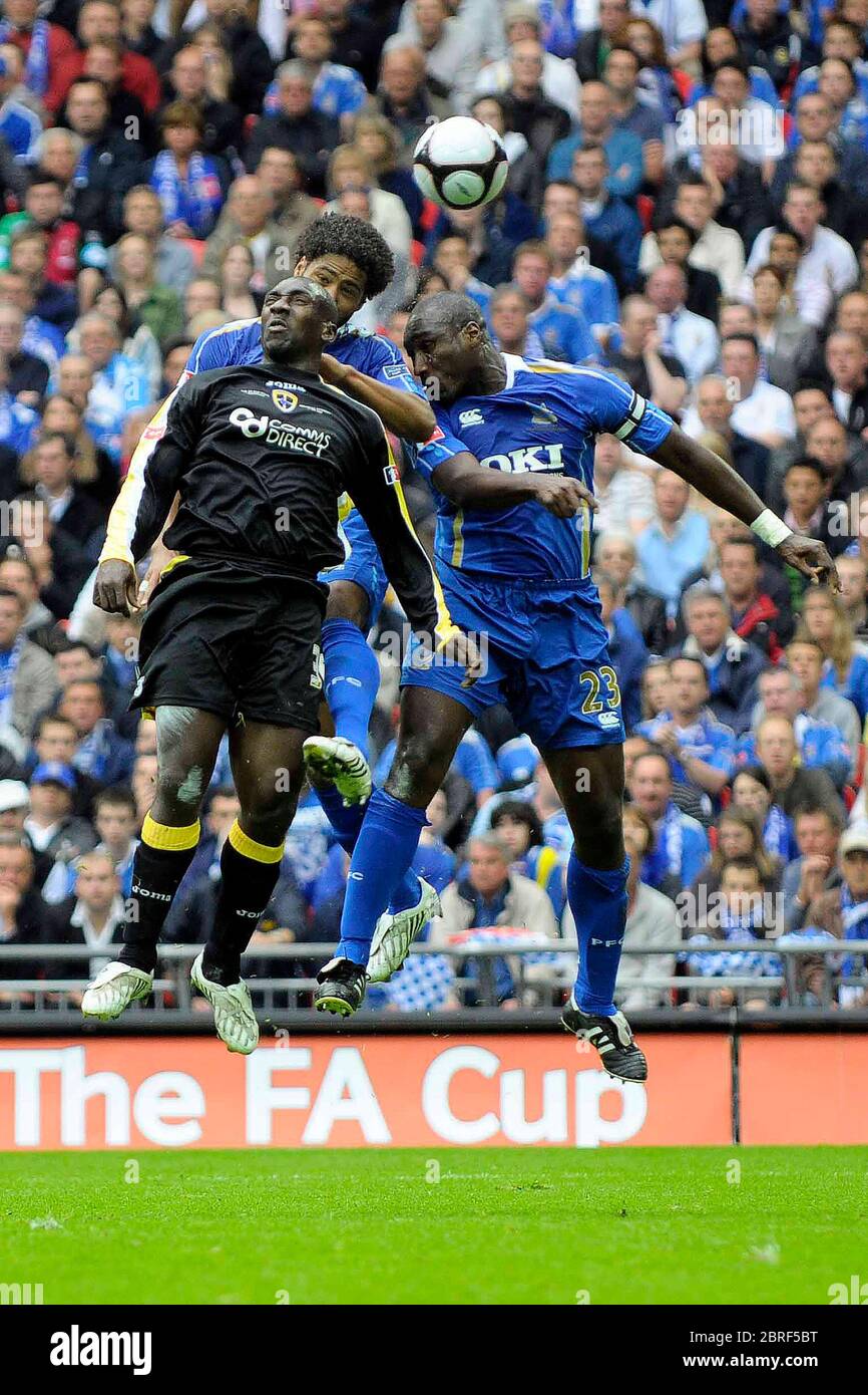 LONDON, UK. MAY 17: Jimmy Floyd Hasselbaink (Cardiff City) challenges both Glen Johnson (Portsmouth) and Sol Campbell (Portsmouth captain) during The Stock Photo