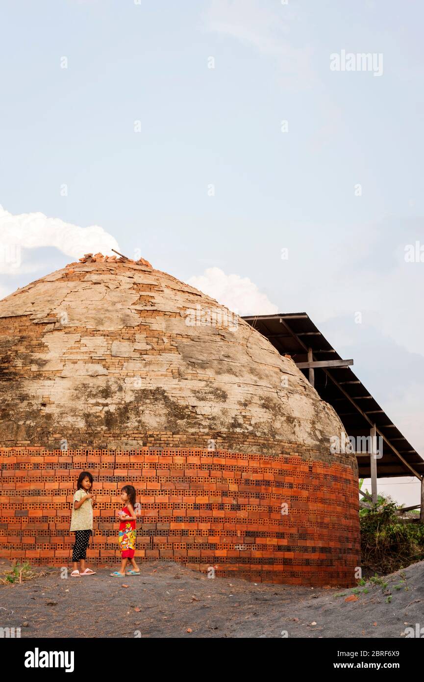 Two young Cambodian girls play together outside a beehive brick kiln. Battambang, Cambodia, Southeast Asia Stock Photo