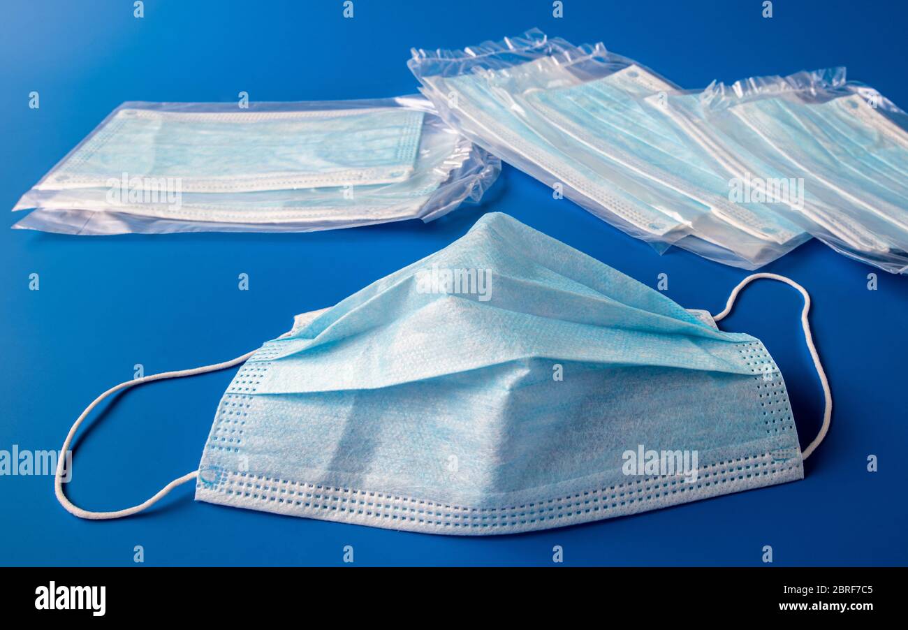 Used disposable and new in packaging medical mask on a blue background ...