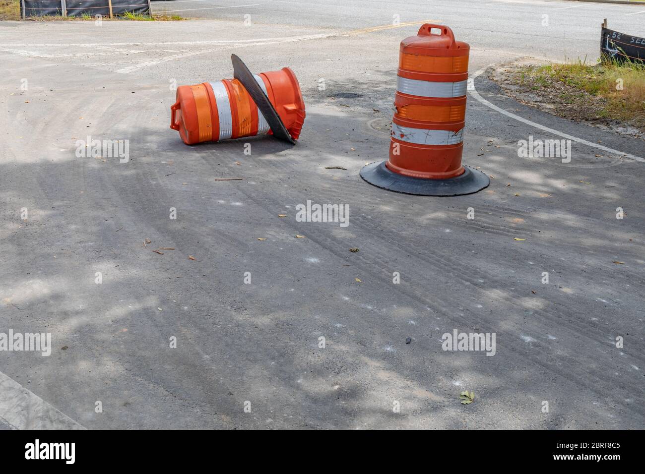 Two traffic barrels, one overturned, metaphor for safe driving, construction zone, accidents, creative copy space, horizontal aspect Stock Photo