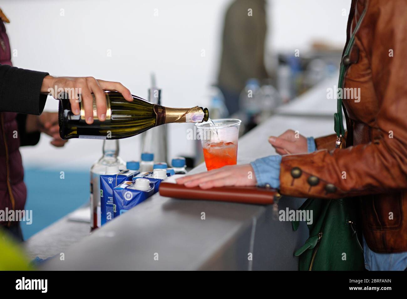 Bartender hand pouring drink from the bottle into the plastic glass