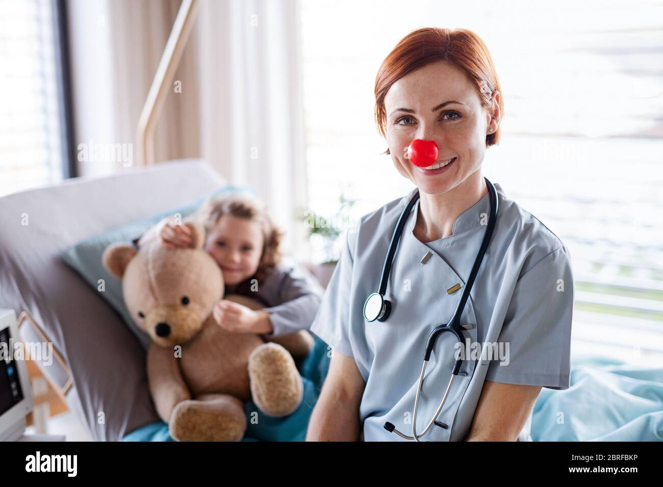 Friendly female doctor examining small girl in bed in hospital Stock ...