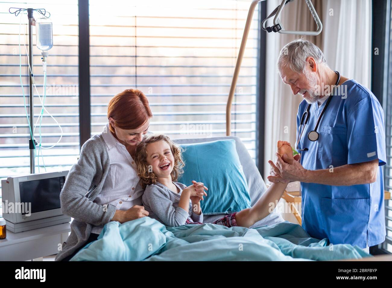 Doctor examining a small hospitalized girl with mother in hospital. Stock Photo