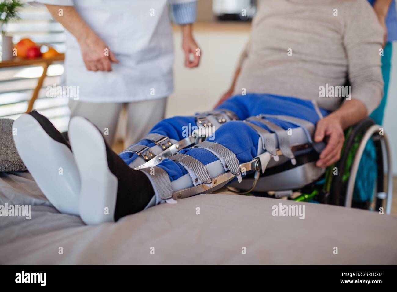 Unrecognizable healthcare worker and paralysed senior patient in hospital. Stock Photo