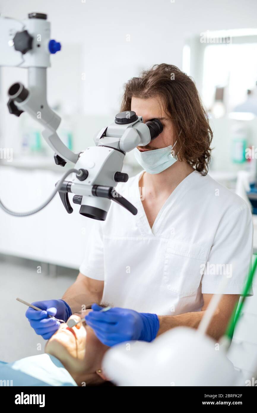 Man dentist with face mask working in dental surgery. Stock Photo
