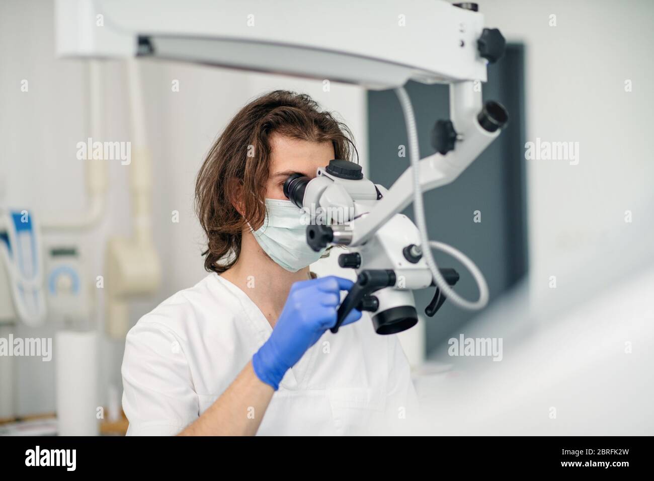 Unrecognizable dentist with face mask working in dental surgery. Stock Photo