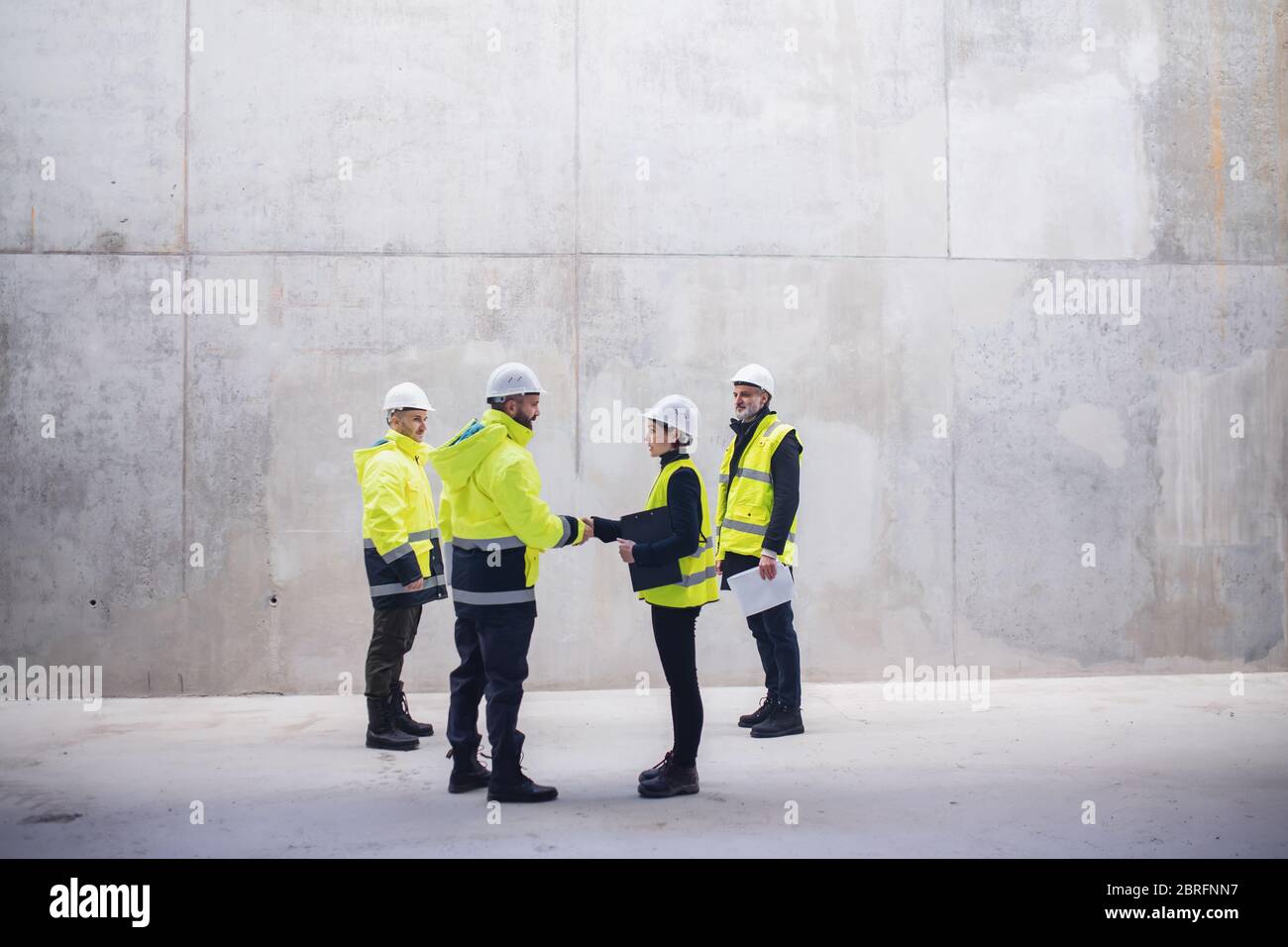 Group of engineers standing on construction site, shaking hands. Stock Photo