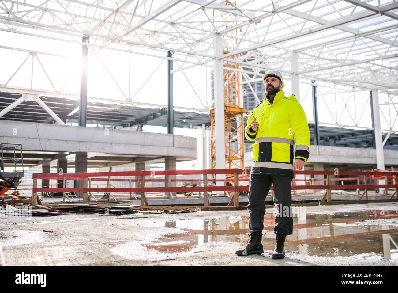 Man engineer standing on construction site, using smartphone. Stock Photo