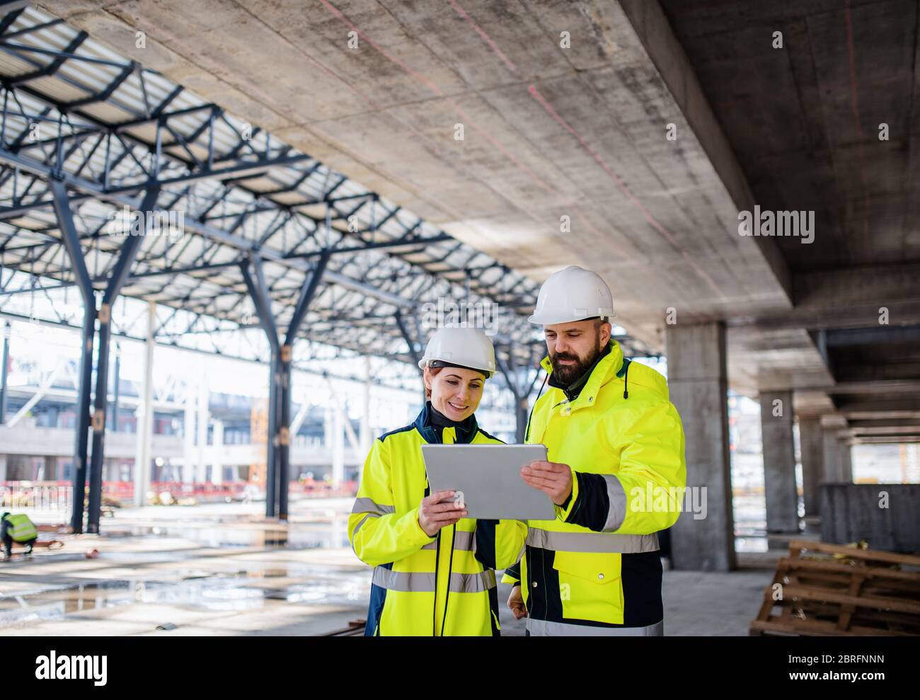 Engineers standing outdoors on construction site, using tablet. Stock Photo