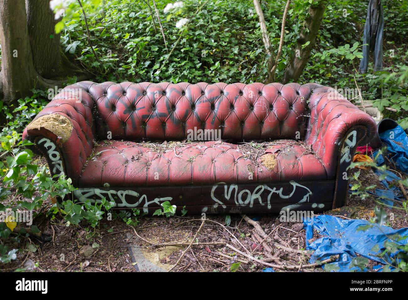 A battered old vintage leather sofa covered in spraycan graffiti