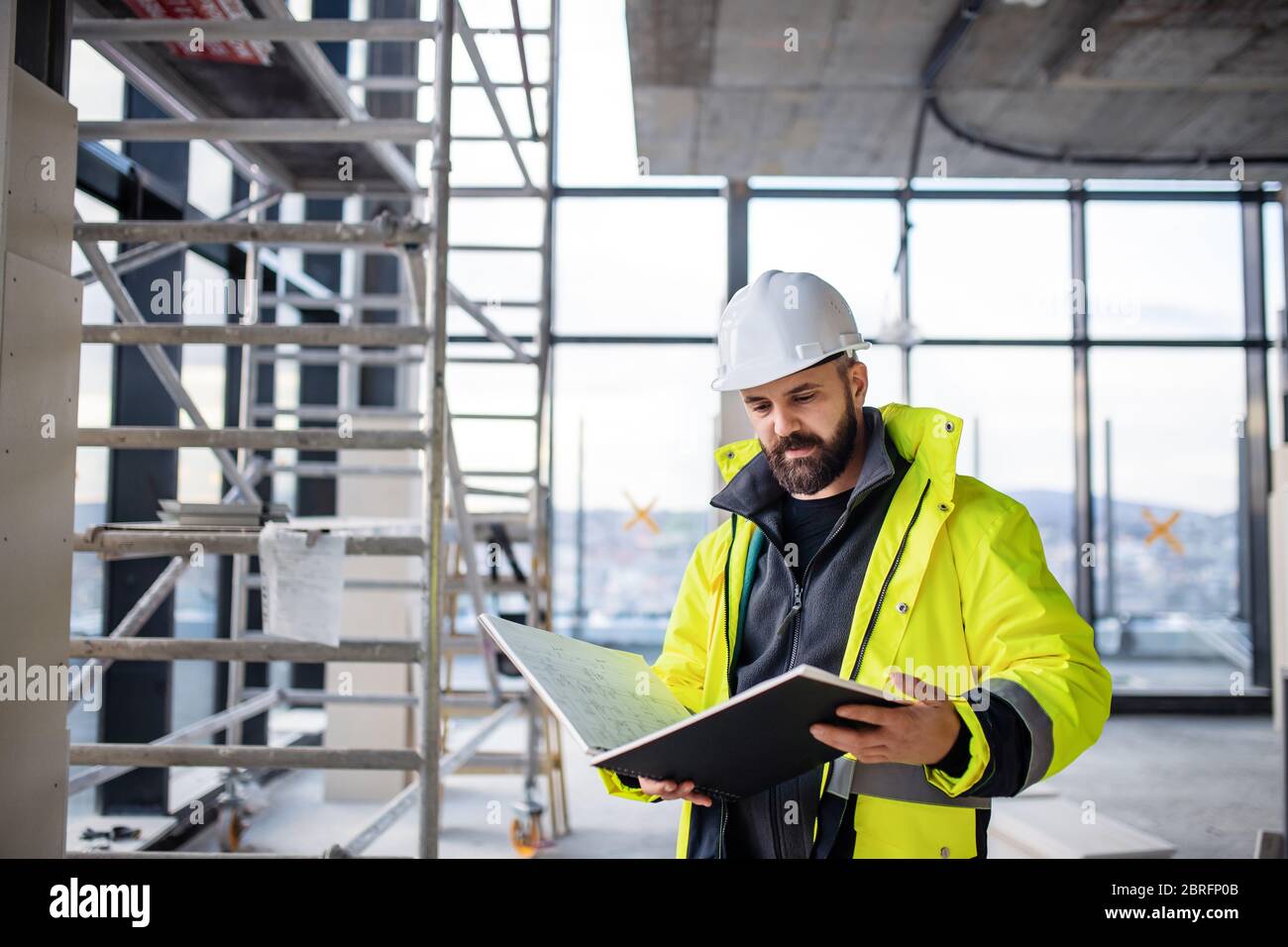Man engineer standing on construction site, holding blueprints Stock ...