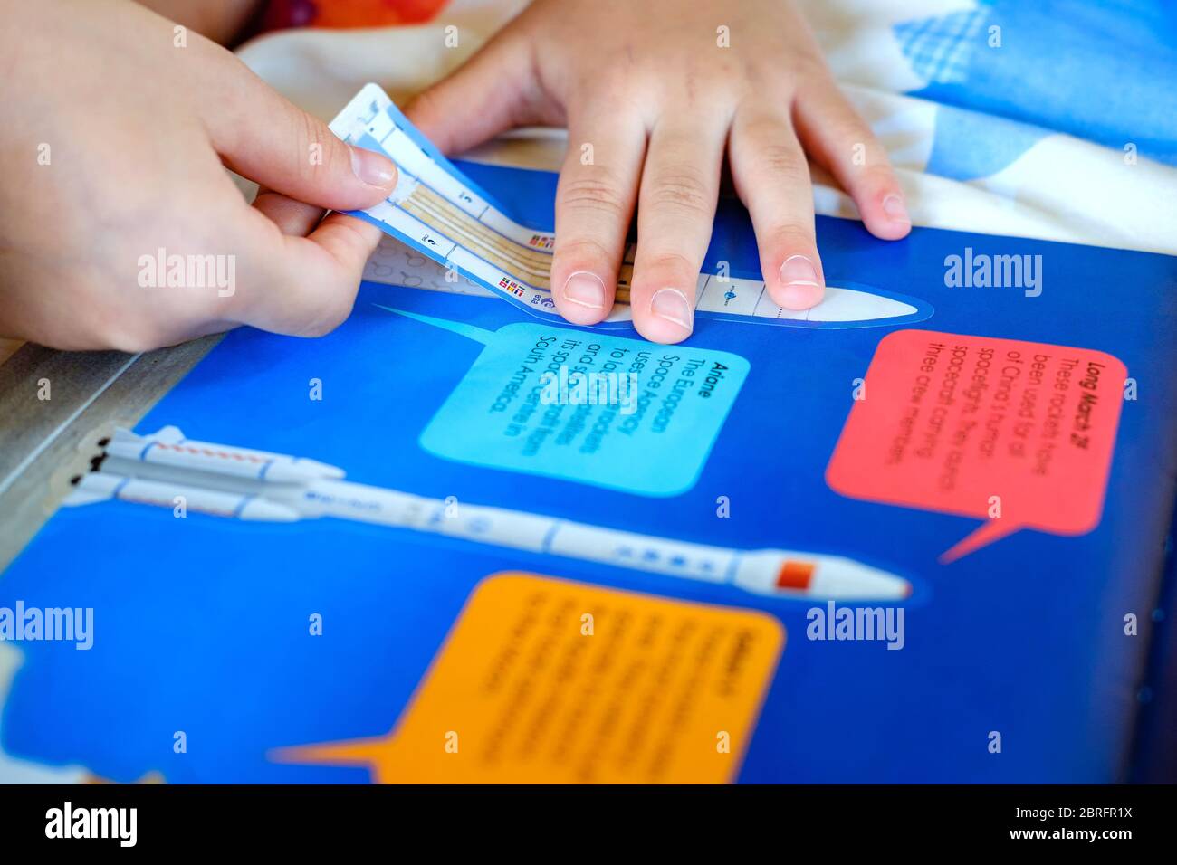 Bangkok, Thailand - May 20, 2020: Child’s hand, Kid’s hand is sticking rocket sticker on space education activity book. Space education activity for s Stock Photo