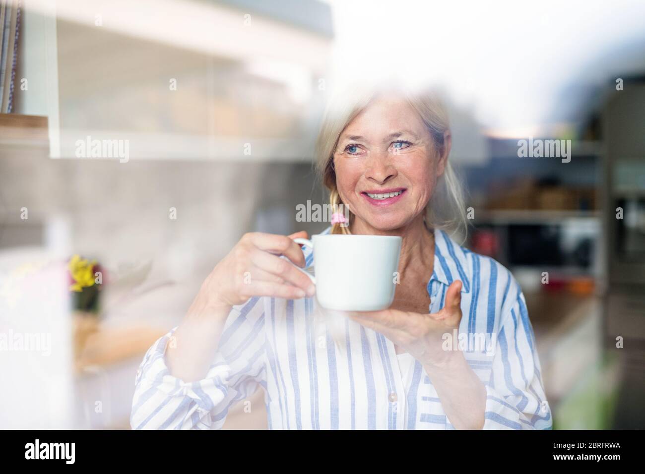 Portrait of senior woman with cup of coffee indoors at home. Stock Photo