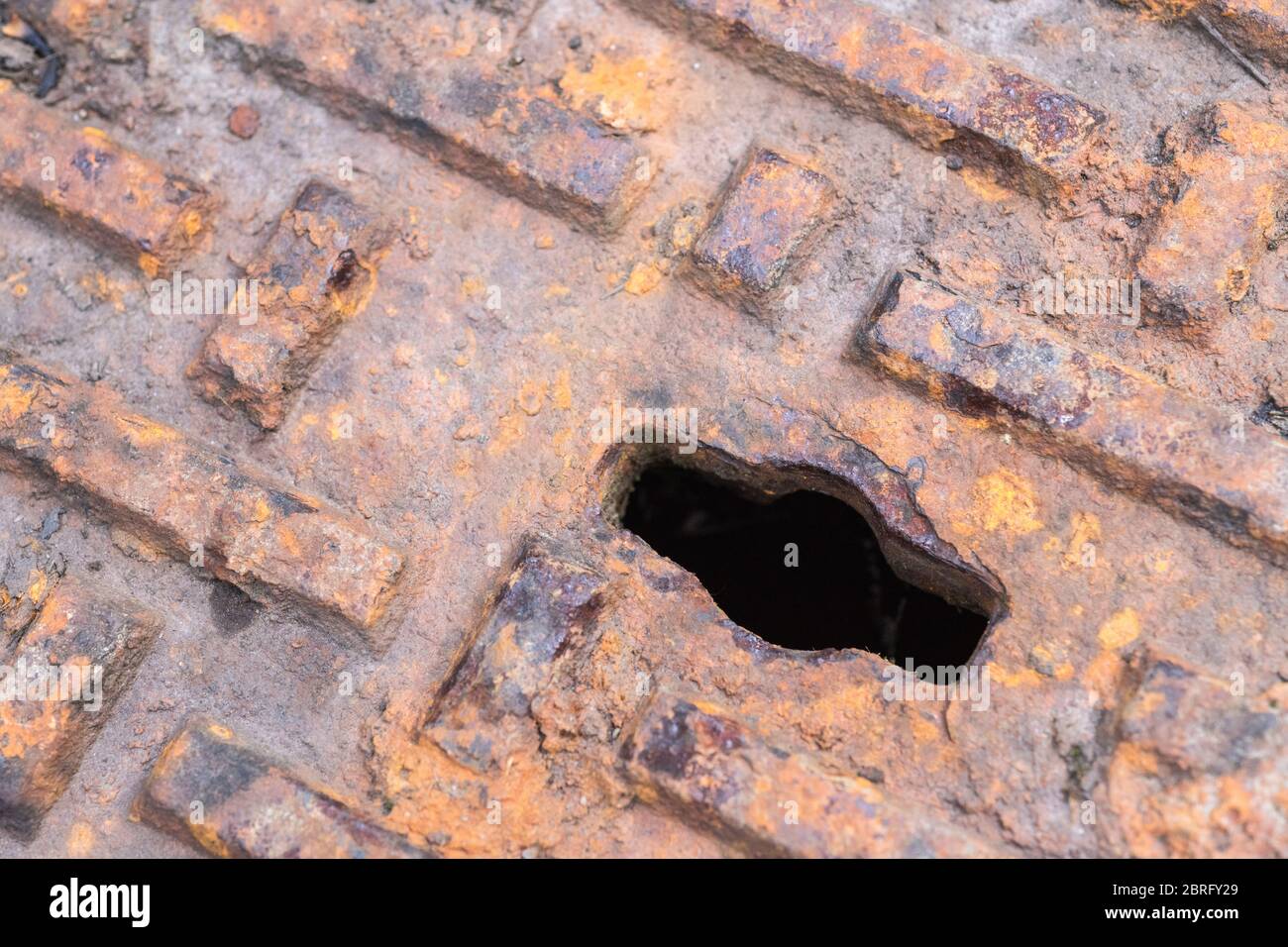 Close shot of rusty inspection cover with lifting keyhole. Abstract darkness, the unknown, what lies beyond. Stock Photo