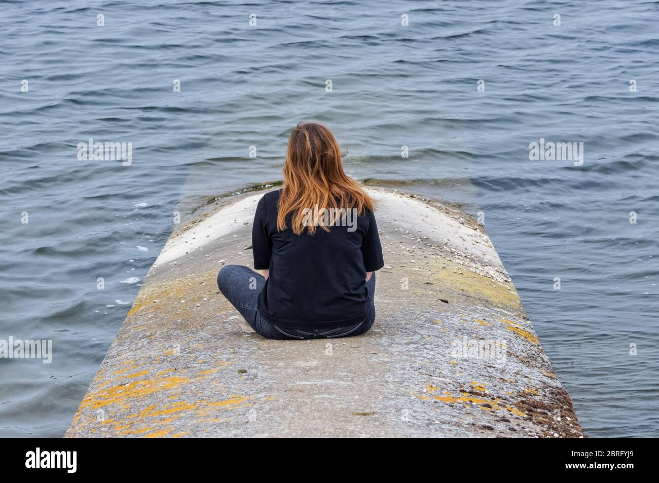 Lonely girl sitting and looking at the lake Stock Photo