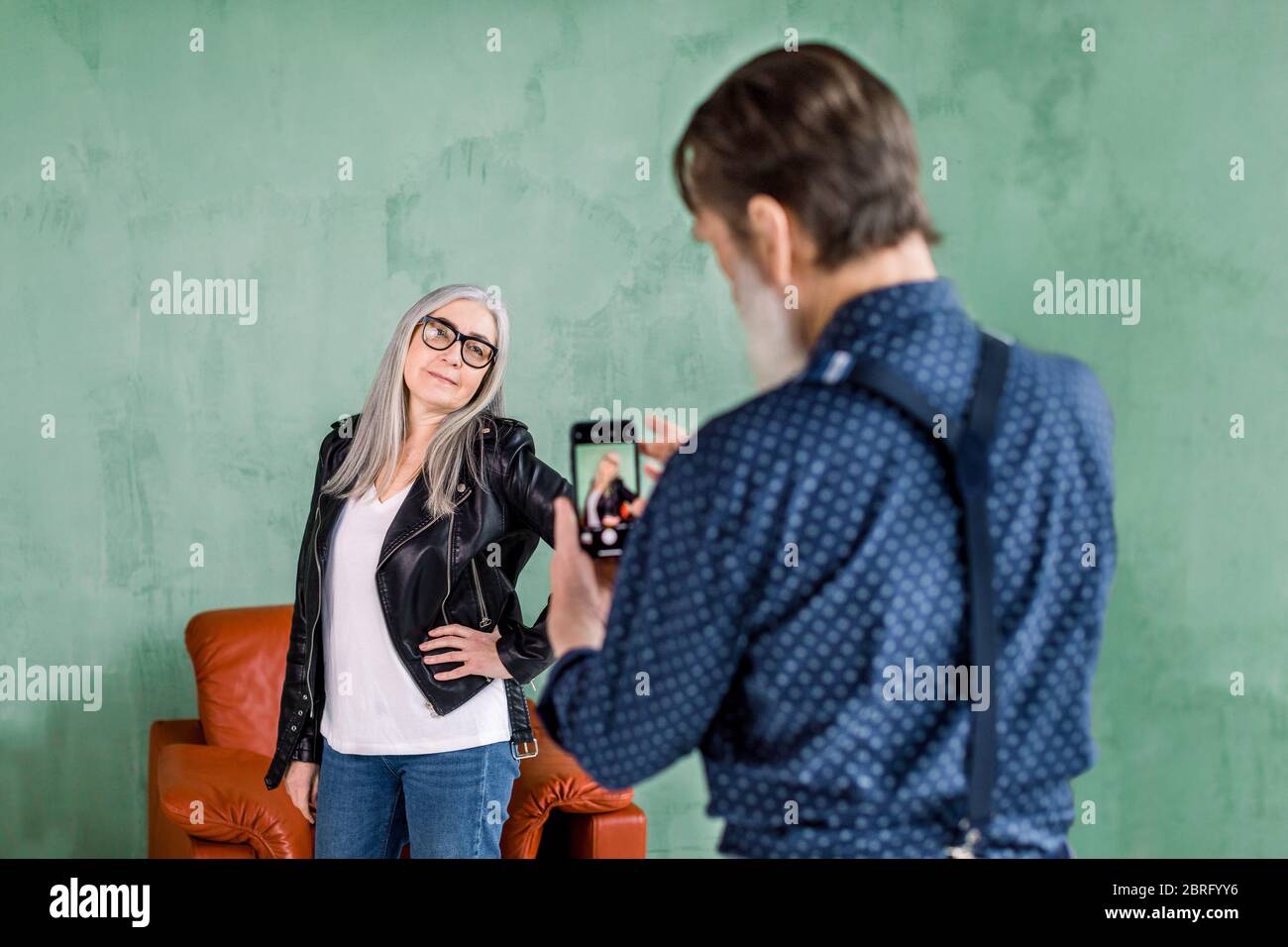 Portrait of handsome elderly man taking picture of his lovely cute beautiful gray haired woman posing to camera and smiling. Senior couple having fun Stock Photo