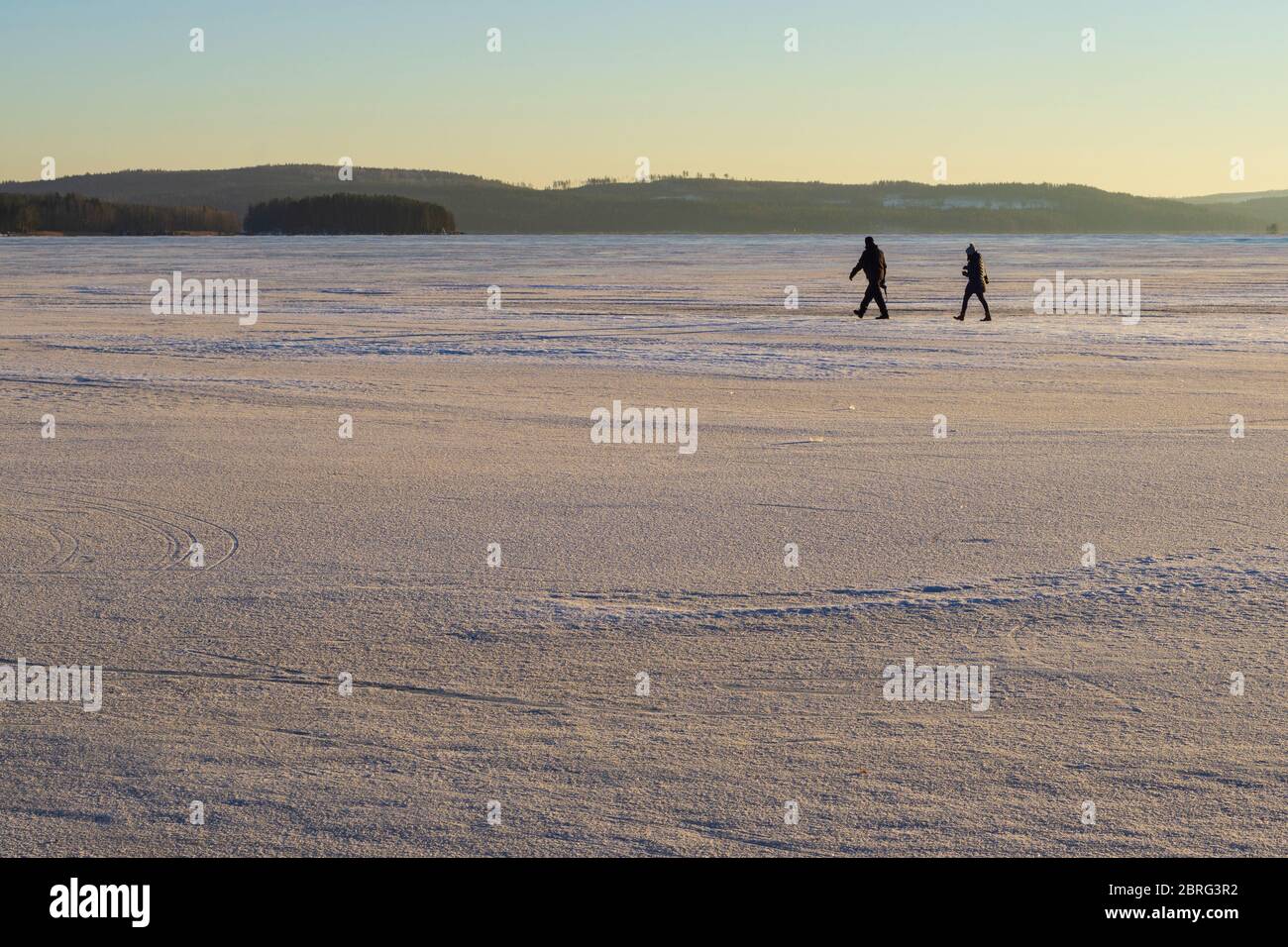 Man and woman walking on ice at frozen Lake Päijänne at Winter , Finland Stock Photo