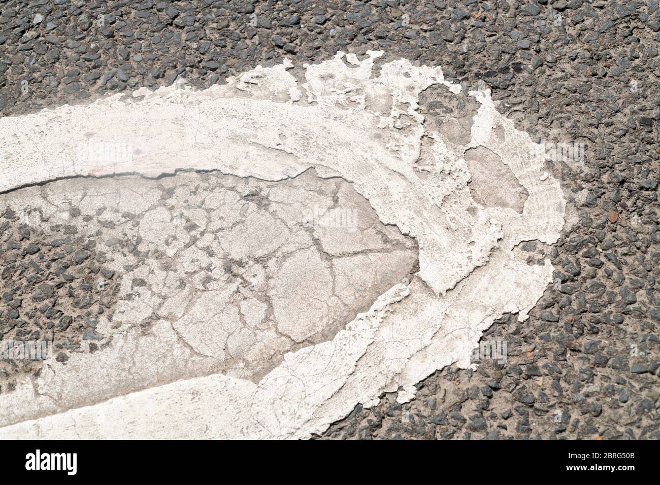 Abstract white road marking paint forming bottom part of O on SLOW. Metaphor road signs, road markings, road network. Stock Photo