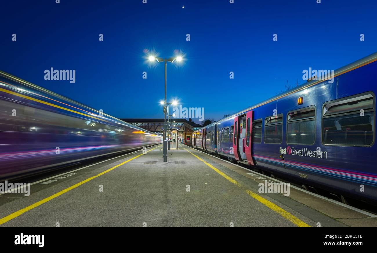 Passenger trains in First Great Western livery at a railway station at dusk in the UK Stock