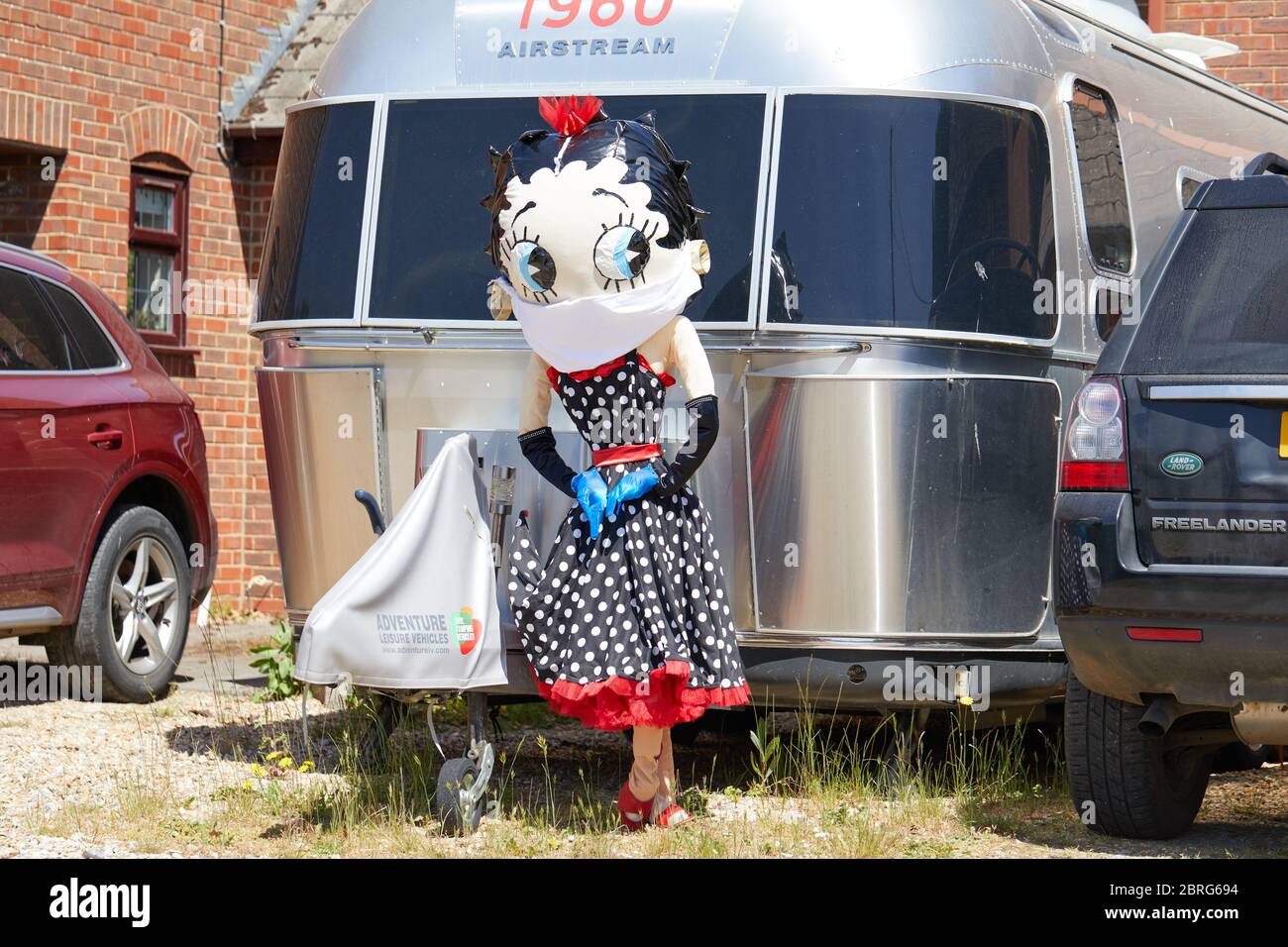 Sandleheath, UK. - May 20, 2020: A Betty Boop scarecrow wearing a face mask. The Hampshire village of Sandleheath holds an annual charity scarecrow competition. Many entries this year adopt a coronavirus theme. Stock Photo