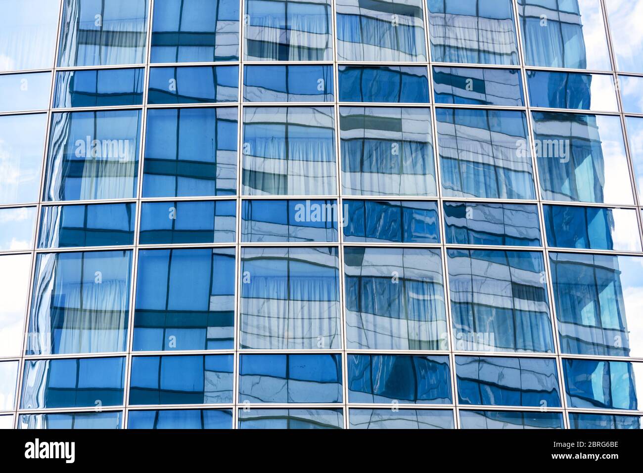 Abstract architecture background. Sky and building are reflected in the office skyscraper facade. Concept of modern urban constructions and business. Stock Photo