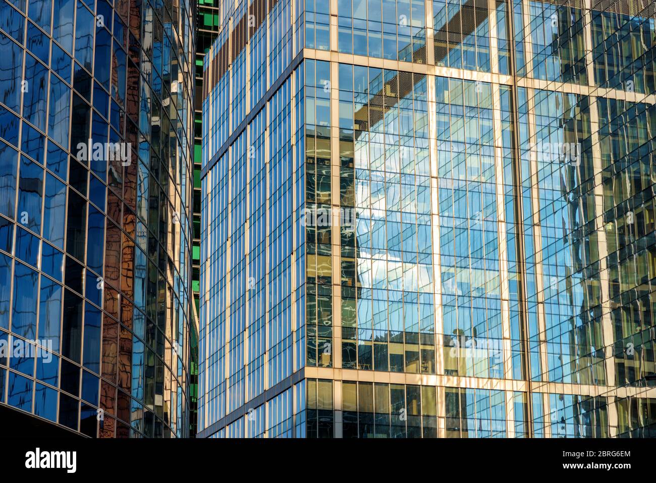 Abstract architecture background. Sky and buildings are reflected in facades of dense office skyscrapers. Steel and glass urban style close-up. Concep Stock Photo