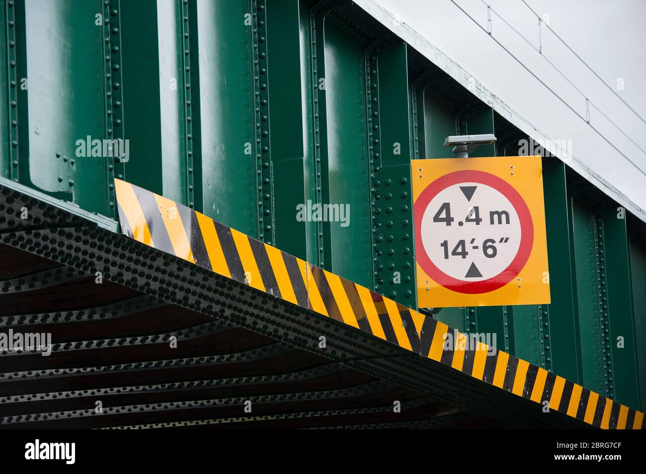 Height limit sign on a railway bridge above a road in the UK. Stock Photo
