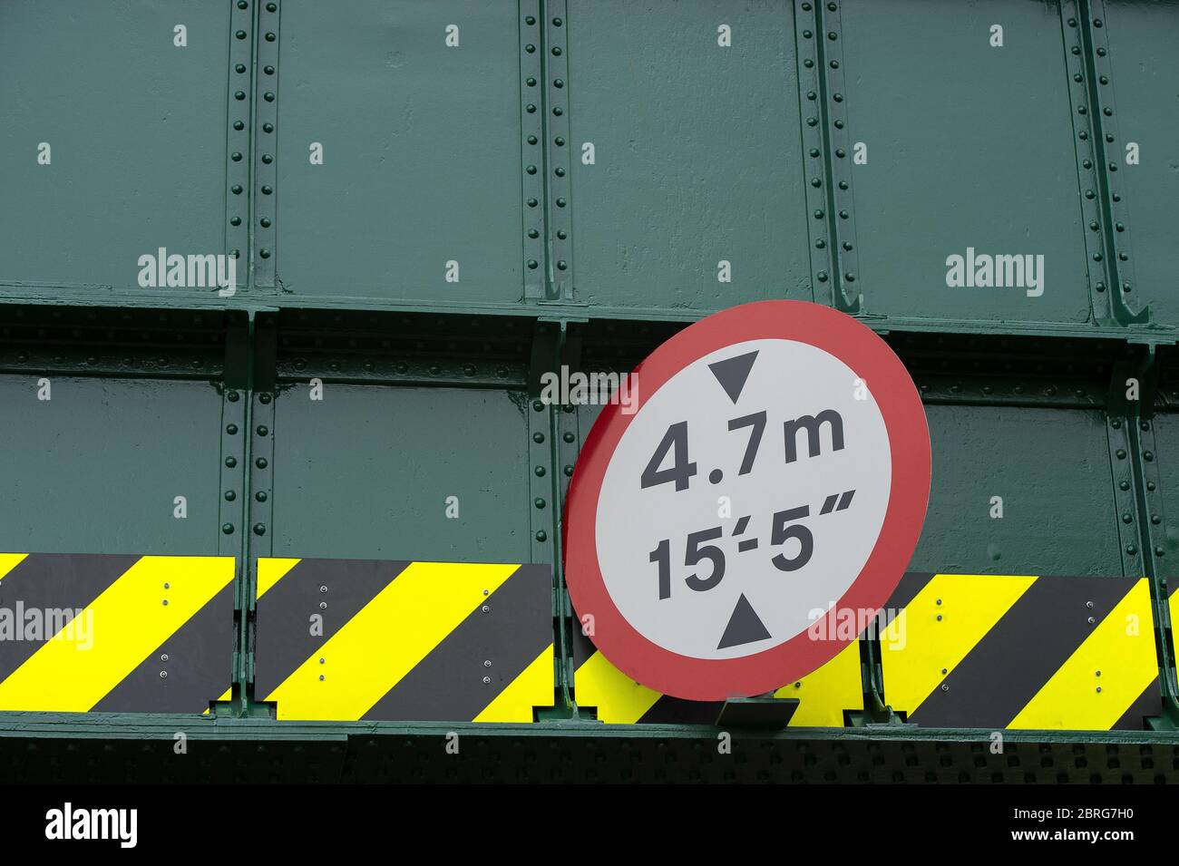 Height limit sign on a railway bridge above a road in the UK. Stock Photo