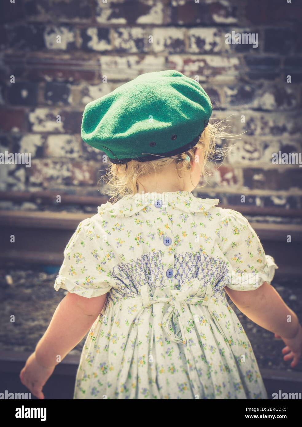 Rear view of cute little girl dressed in 1940s fashion as child of wartime WW2 Britain, 1940s heritage railway summer event. Vintage child from behind. Stock Photo