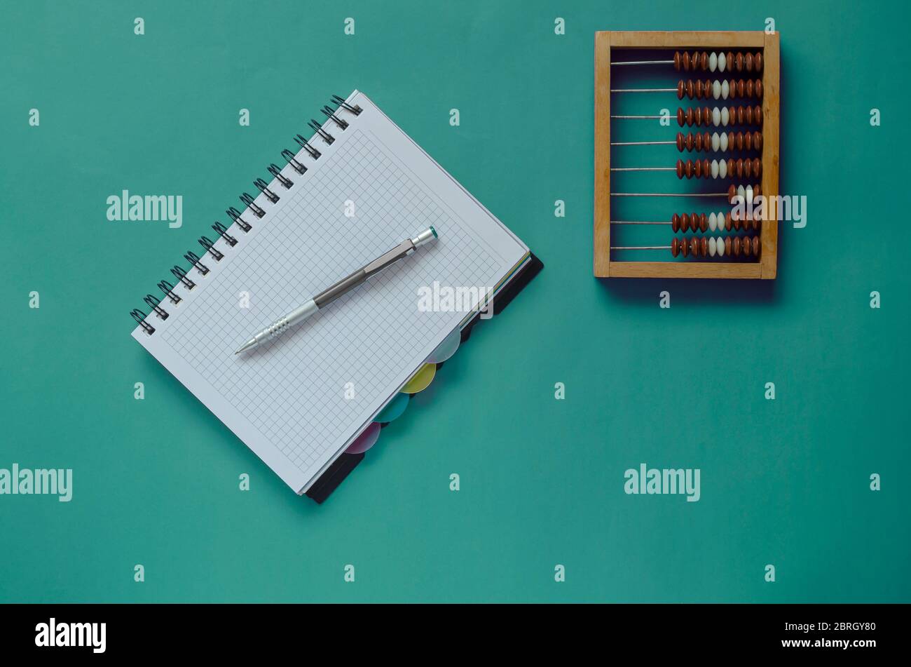 Creative turquoise background with wooden abacus, notebook and pen 