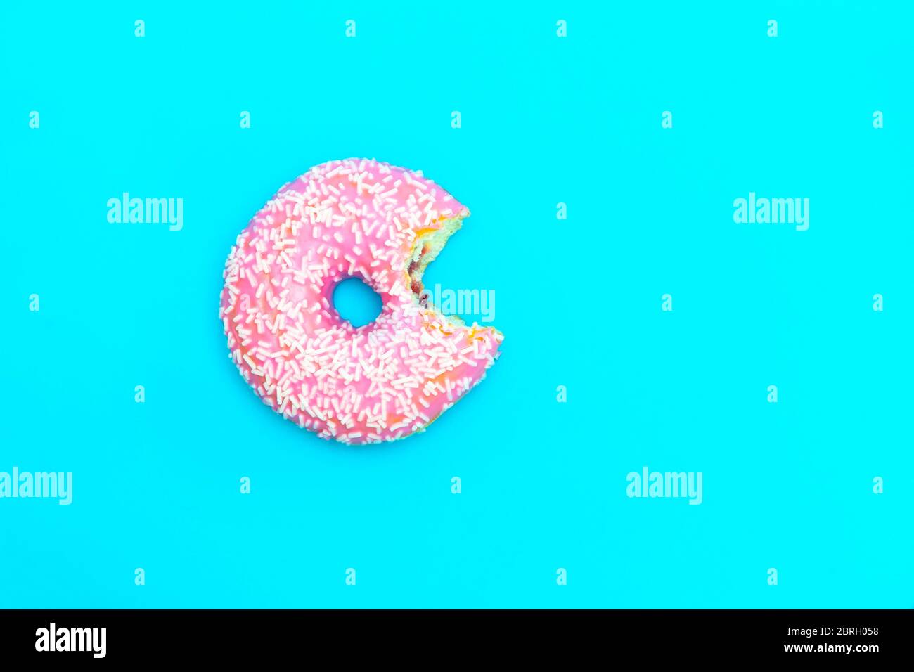 Top view of bitten glazed donut on blue background with copy space ...