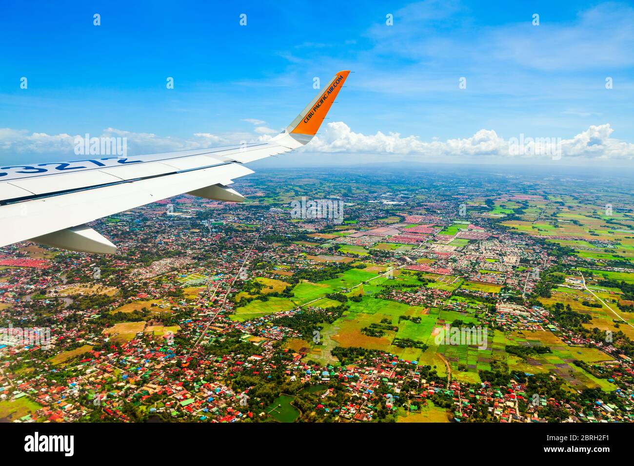 MANILA, PHILIPPINES - FEBRUARY 23, 2013: Cebu Pacific airplane wing above the Manila city suburbs in Philippines Stock Photo