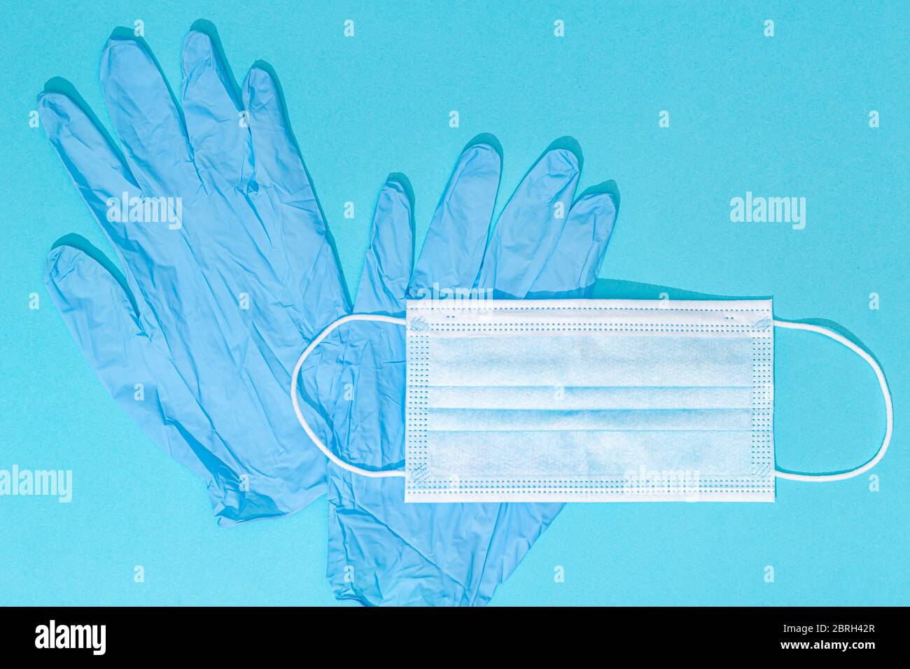 Medical face mask and protective gloves blue background. Coronavirus COVID-19 protection concept. Copy space. Top view Stock Photo