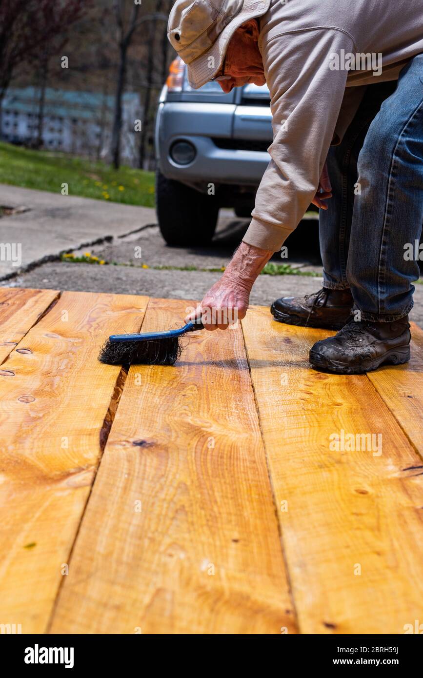 A man paints boards with linseed oil to treat them for use in a raised