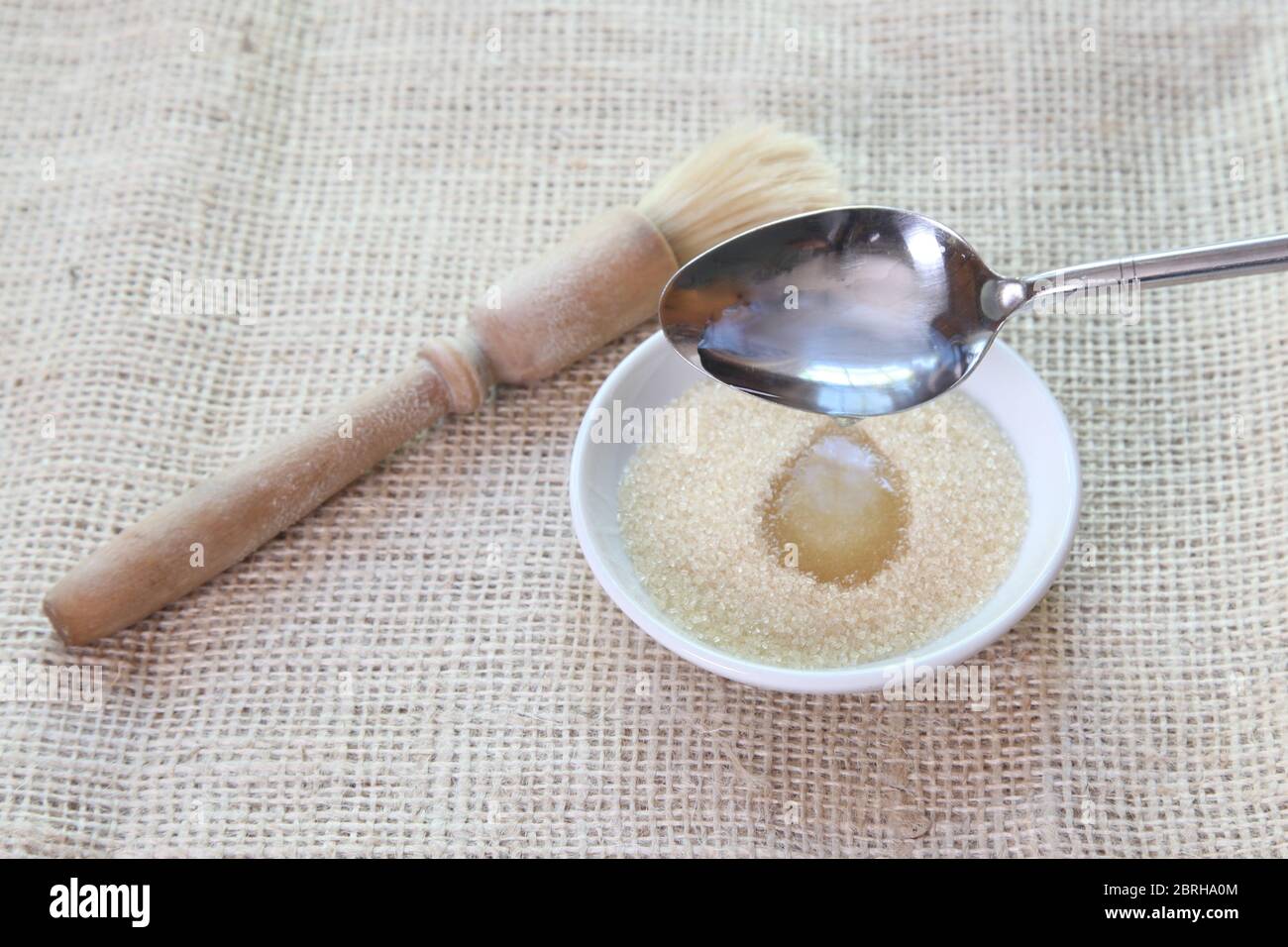Making a sugar syrup paste by adding water to unrefined granulated sugar for brushing on top of buns - Sally Lunn baking series of images Stock Photo